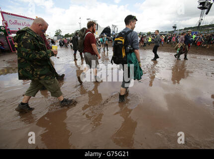 Glastonbury Festival 2014 - Tag 1. Festivalbesucher, die beim Glastonbury Festival auf der Worthy Farm in Somerset durch eine Schlammpfütze wandern. Stockfoto