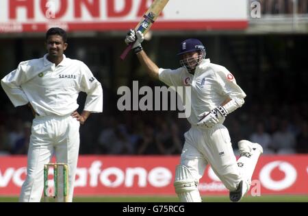 Der englische Opener Michael Vaughan feiert sein Jahrhundert, während Bowler Anil Kumble am vierten Tag des 1. Tests gegen Indien bei Lord's anschaut. Stockfoto