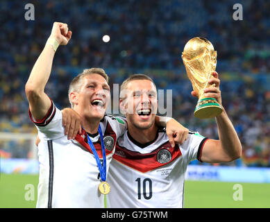 Deutschlands Bastian Schweinsteiger (links) und Lukas Podolski feiern am Pitch mit der FIFA World Cup 2014 Trophy Stockfoto