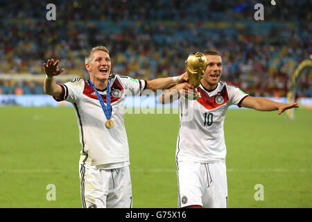 Fußball - FIFA Fußball-Weltmeisterschaft 2014 - Finale - Deutschland gegen Argentinien - Estadio do Maracana. Die Deutschen Bastian Schweinsteiger und Lukas Podolski (rechts) feiern mit der WM-Trophäe Stockfoto