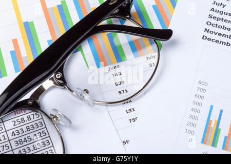 Schuss aus einem Paar von schwarz umrandeten Specticles auf einen Graphen und einer Tabellenkalkulation auf ein Buchhalter Desktop hautnah Stockfoto