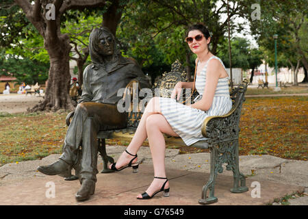 Eine Frau sitzt mit der Statue von John Lennon John Theodore Lennon Park in Havanna, Kuba Stockfoto