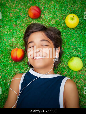 Portrait eines niedlichen lächelnde Teen jungen Musik anhören, liegend auf einer frischen grünen Wiese, glücklich Sommerwochenende Stockfoto