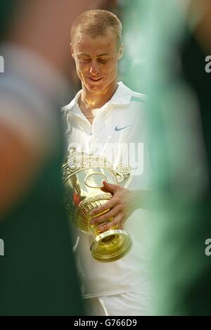 KEINE KOMMERZIELLE NUTZUNG. Der weltbeste Aussaat Lleyton Hewitt aus Australien umarmt die Trophäe, nachdem er David Nalbandian aus Argentinien beim Finale der Herren-Singles in Wimbledon besiegt hat. Die Tennismeisterschaften im All England Lawn Tennis Club ist das erste Mal, dass Nalbandian auf dem Rasen Tennis gespielt hat. Hewitt gewann in den geraden Sätzen 6:1/6:3/6:2. Stockfoto