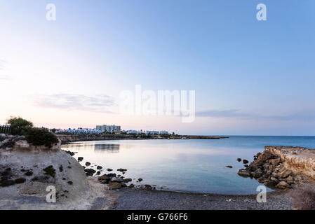 Foto des Meeres in Protaras, Zypern-Insel, mit Felsen und Hotels bei Sonnenuntergang. Stockfoto