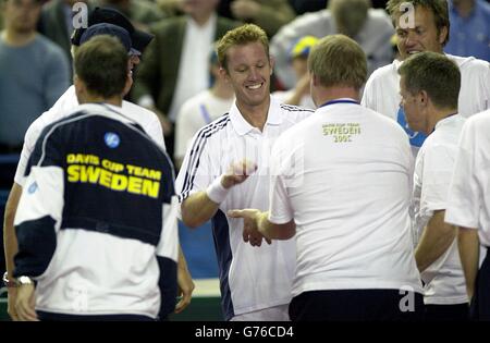 Der Schwede Thomas Johansson (gegenüberliegende Kamera) wird von seinem Team gratuliert, nachdem er den Briten Greg Rusedski beim Finale und entscheidenden Spiel im Davis Cup World Group Spiel in der National Indoor Arena, Birmingham, geschlagen hat. Stockfoto