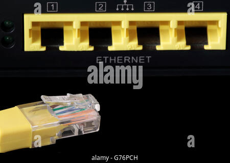 Vordergrund ein gelbes Netzwerkkabel und vier Netzwerkanschlüsse am unteren Stockfoto