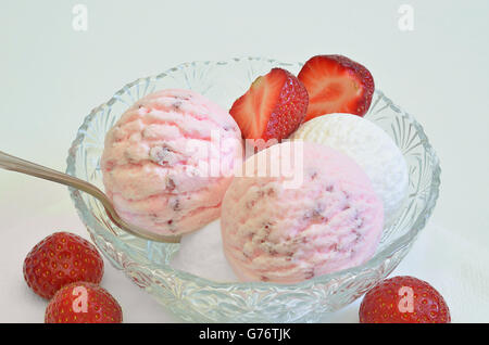 Kugeln Erdbeereis und Vanilleeis in eine Schale mit frischen Erdbeeren, Makro, Detail, weißer Hintergrund Stockfoto