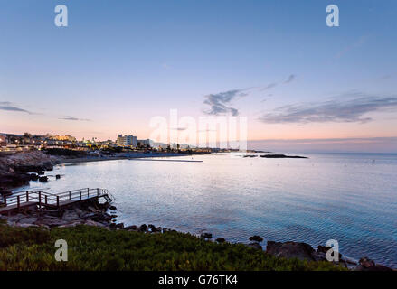 Foto des Meeres in Protaras, Zypern-Insel, mit Felsen und Hotels bei Sonnenuntergang. Stockfoto