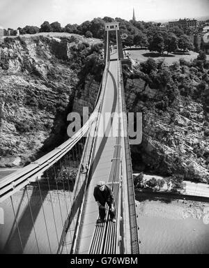 Der vielleicht höchste und coolste Schmierjob in Großbritannien wird von diesem Arbeiter ausgeführt, der mit Sicherheit an den steilen Ketten der Clifton Suspension Bridge, 330 Meter über dem Fluss Avon, Bristol, steht. Er inspiziert und ölt die Gelenke an den Ketten der Brücke. Die Brücke wurde von Isambard Kingdom entworfen und 1864 fertiggestellt. Stockfoto