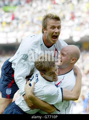 Der englische Michael Owen wird von den Teamkollegen Danny Mills (rechts) und David Beckham (oben) nach dem Treffer gegen Brasilien beim WM-Viertelfinale im ecopa Stadium, Shizuoka, Japan, gratuliert. Stockfoto