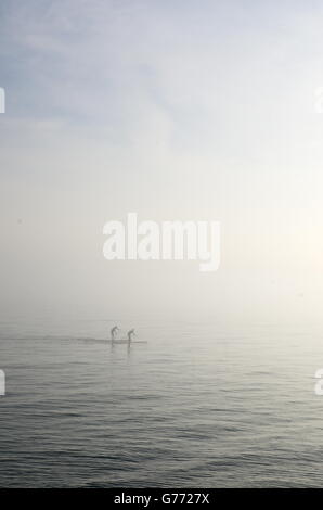 Zwei Paddleboarders machen ihren Weg durch den Nebel in Hove. Stockfoto