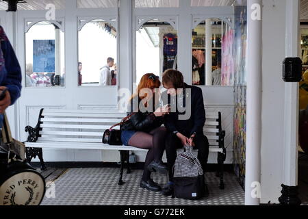 Ein junges Paar sitzt auf einer weißen Bank SMS. Stockfoto