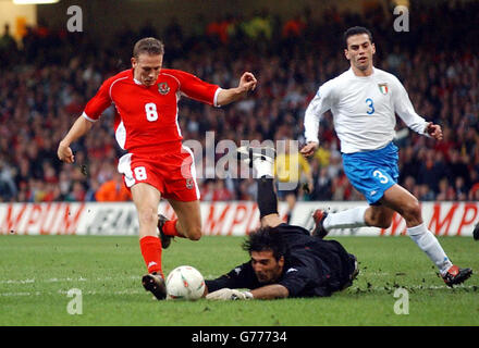 Craig Bellamy aus Wales (links) nimmt den Ball um die ausgestreckten Hände des italienischen Torwarts Gianluigi Buffon, um beim Qualifikationsspiel zur EM 2004 im Millennium Stadium, Cardiff, das zweite Tor seiner Seite zu erzielen. Stockfoto