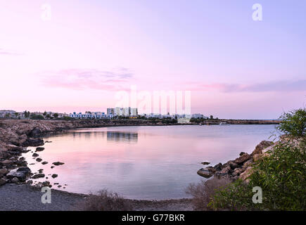 Foto des Meeres in Protaras, Zypern-Insel, mit Felsen und Hotels bei Sonnenuntergang. Stockfoto