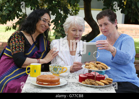 Die Schauspielerin June Whitfield (Mitte) und die Rentner Chitra Banarjee (links) und Patricia Mary SIM genießen Tee und Texte, um den EE National Techy Tea Party Day bei Age UK in East London zu starten. Stockfoto