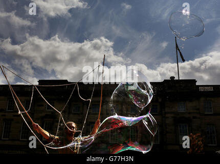 Mr Bubbles, einer der Edinburgh Fringe Festival-Acts, bläst vor dem Beginn des Festivals in dieser Woche Blasen vor einer Menge von Mitgliedern der Öffentlichkeit in Edinburghs Royal Mile. Stockfoto