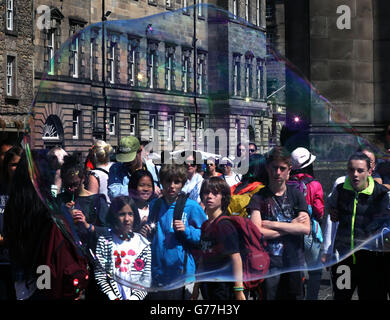 Mr Bubbles, einer der Edinburgh Fringe Festival-Acts, bläst vor dem Beginn des Festivals in dieser Woche Blasen vor einer Menge von Mitgliedern der Öffentlichkeit in Edinburghs Royal Mile. Stockfoto