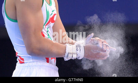 Der walisische Iwan Mepham streicht ihm Kreide aus den Händen, bevor er während des Mannschaftsfinales und der Einzelqualifikation im SEE Hydro während der Commonwealth Games 2014 in Glasgow an den Ringen antritt. Stockfoto