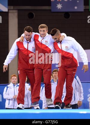 Englands Sam Oldham (Mitte) wird von Kristian Thomas (links) und Louis Smith auf das Podium gebracht, nachdem England bei den Commonwealth Games 2014 in Glasgow beim SSE Hydro Gold im Mannschaftsfinale der Artistic Gymnastic Männer gewonnen hatte. Stockfoto