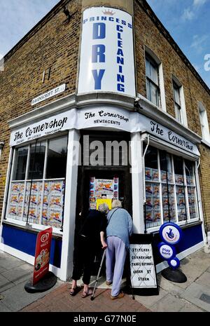 Zwei Anwohner versuchen, einen Blick in den Cornershop in Wellington Row, Bethnal Green, East London, zu werfen, eine Kunstinstallation der Textilkünstlerin Lucy Sparrow, in der fast 2,000 klassische Lebensmittel im Inneren aus Filz handgefertigt werden und als Kunstwerk verkauft werden. Stockfoto