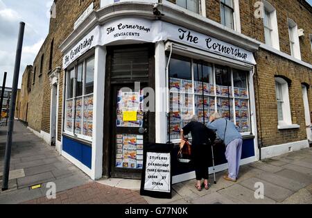 Zwei Anwohner versuchen, einen Blick in den Cornershop in Wellington Row, Bethnal Green, East London, zu werfen, eine Kunstinstallation der Textilkünstlerin Lucy Sparrow, in der fast 2,000 klassische Lebensmittel im Inneren aus Filz handgefertigt werden und als Kunstwerk verkauft werden. Stockfoto