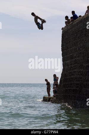 In Brighton, East Sussex, springen Menschen von der Meeresschutzanlage ins Wasser, während die Temperaturen im ganzen Land steigen. Stockfoto