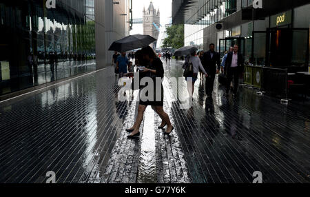 Die Öffentlichkeit wird in der Nähe der London Bridge, London, von starkem Regen erfasst. Stockfoto