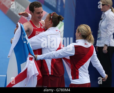 Der englische Alistair Brownlee wird am Ende des Rennens von den Teamkollegen Jodie Stimpson und Vicky Holland gratuliert, nachdem er bei den Commonwealth Games 2014 in der Nähe von Glasgow den Mixed Team Relay im Strathclyde Country Park gewonnen hatte. Stockfoto