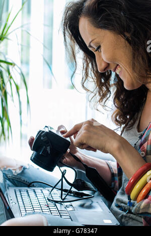 glückliche Frau Scheck Fotos vor der Kamera beim Sitzen auf dem sofa Stockfoto