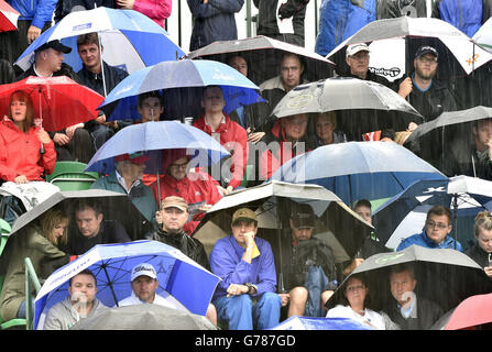 Am dritten Tag der Open Championship 2014 im Royal Liverpool Golf Club, Hoylake, schützen sich die Zuschauer vor dem Regen auf dem 1. Loch. Stockfoto