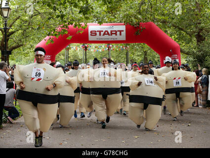 Die Teilnehmer starten den Sumo Run - einen 5 km langen Charity-Lauf für Läufer in aufblasbaren Sumo-Anzügen - im Battersea Park, London. Stockfoto