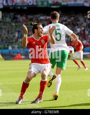 Wales' Gareth Bale (links) Rechtsmittel nach dem Ball erschien, den Arm des Nordirlandes Jonny Evans (rechts) während der Runde der 16 Spiel im Parc de Princes, Paris getroffen. Stockfoto