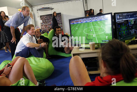 Der Herzog von Cambridge sieht Prinz Harry bei einem Besuch im Commonwealth Games Village in Glasgow ein Videospiel spielen. P Stockfoto