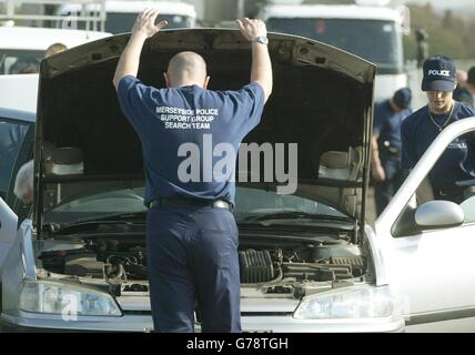 Polizeibeamte von Merseyside suchen Fahrzeuge, wenn sie die Aintree-Rennbahn vor dem Martell Grand National 2003 in Aintree, Liverpool, betreten. Stockfoto