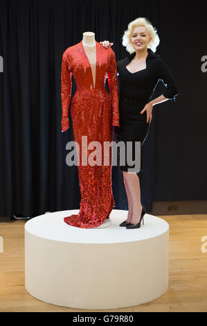 Eine Frau, die als Marilyn Monroe gekleidet ist, neben einem roten Paillettenkleid, das von Marilyn Monroe in Gentlemen Prefer Blondes getragen wird, das Teil der berühmten und berüchtigten Ausstellung ist, die Highlights aus der Sammlung des Jersey-Sammlers David Gainsborough Roberts bei Christie's in London enthält. Stockfoto