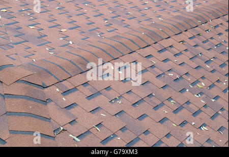 Draufsicht der braunen Dachschindeln mit ein paar abgefallenen Blättern auf der Oberfläche. Selektiven Fokus mit einem unscharfen Hintergrund. Stockfoto