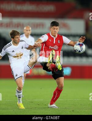 Alex Revell von Rotherham United wird während des zweiten Spiels des Capital One Cup im Liberty Stadium, Swansea, von Tom Carroll von Swansea City herausgefordert. Stockfoto