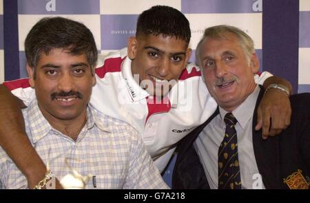 Amir Khan (Mitte) aus Bolton, ein Olympiasieger mit Silbermedaille, wird von seinem Vater Shajaad (links) und seinem Trainer Mike Jelley begleitet, während er während einer Pressekonferenz in der Bolton Arena spricht. Khan enthüllte, wie der kürzlich pensionierte Olympiasieger, der Kubaner Mario Kindelan, ihn dazu drängte, sich der Verlockung der Professionalität zu widersetzen und sich auf die nächsten Spiele in Peking zu konzentrieren. Stockfoto