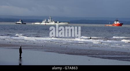 Eine Statue von einem anderen Ort von Antony Gormley ist im Vordergrund zu sehen, als HMS Plymouth von Liverpool weggeschleppt wird, um verschrottet zu werden. Das Kriegsschiff war Teil der Mission während des Falklandkrieges und ist auf dem Weg in die Türkei, wo es verschrottet wird. Stockfoto