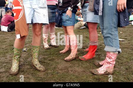 Festivalbesucher ziehen am ersten Tag des Carling Weekend: Reading Festival in Reading ihre Gummistiefel an, um dem Schlamm zu trotzen. Das jährliche dreitägige Festival findet gleichzeitig in Reading und Leeds statt. Stockfoto