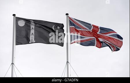 Die Flagge der Ahmadiyya Muslim Community fliegt neben der Unionsflagge, während sich Ahmadiyya-Muslime im Hauptzelt zum Freitagsgebet versammeln, während sie sich während der Jalsa Salana UK 2014 in Alton, Hampshire, mit bis zu 30,000 Muslimen zusammentaren, um dem Kalifen Treue zu versprechen. Stockfoto