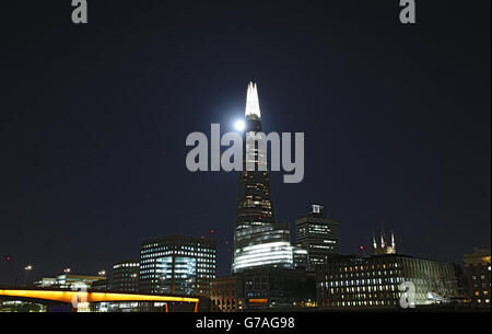 Ein Blick auf den "Supermond" oder Perigee Mond, der hinter dem Shard Gebäude in London aufsteigt. Stockfoto