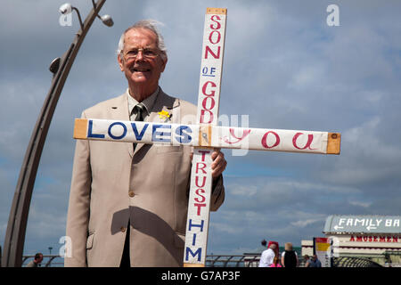 Philip Gascoigne, ein Laienprediger mit einem Holzkreuz; Open-Air-Evangeliumspredigen, Straßenpredigen, biblische Evangelisierung eines religiösen Glaubens oder öffentliche Predigt; ein Mann, der seine Botschaft der Liebe und religiösen christlichen Werten an die Küste in Blackpool, Lancashire, Großbritannien bringt Stockfoto