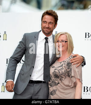 Gerard Butler posiert mit einem Mitglied der Öffentlichkeit während einer Auftaktveranstaltung für Boss Bottled im Westfield Shopping Centre, Shepherds Bush, London. Stockfoto