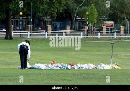 Ein Polizist legt einen Blumenstrauß auf die Stelle, an der ein französischer Student ermordet wurde, auf Twickenham Green, London. Amelie Delagrange, 22, wurde am Donnerstagabend in Twickenham im Südwesten Londons getötet, nachdem sie an der falschen Bushaltestelle aussteigen und nach Hause gehen musste. Die Polizei hat nicht ausgeschlossen, dass sie Opfer eines seriellen Angreifers gewesen sein könnte. Stockfoto