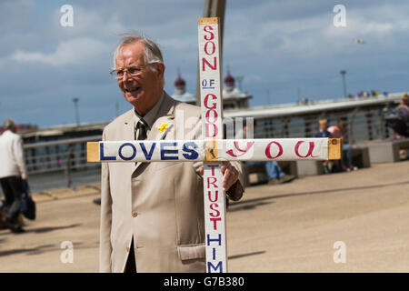 Philip Gascoigne, ein Laienprediger mit einem Holzkreuz; Open-Air-Evangeliumspredigen, Straßenpredigen, biblische Evangelisierung eines religiösen Glaubens oder öffentliche Predigt; ein Mann, der seine Botschaft der Liebe und religiösen christlichen Werten an die Küste in Blackpool, Lancashire, Großbritannien bringt Stockfoto