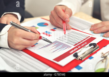 menschliche Hände analysieren Geschäftsdiagramme im Vordergrund Stockfoto