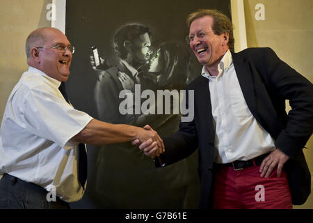 Dennis Stinchcombe vom Broad Plain Boys' Club in Bristol, links, und der Bürgermeister von Bristol, George Ferguson, schütteln die Hände, als der Verkauf und die Übergabe eines Banksy-Kunstwerks mit dem Titel 'Mobile Lovers' im Bristol Museum & Art Gallery abgeschlossen wurde, wo es der Öffentlichkeit gezeigt wurde. Stockfoto