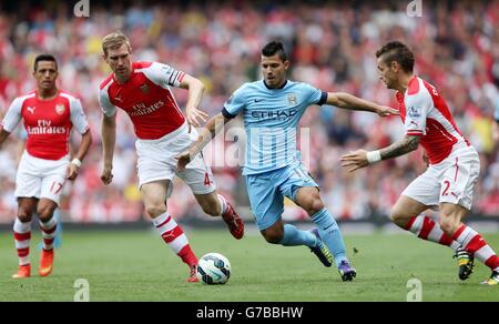 Sergio Aguero von Manchester City (rechts) wird während des Spiels der Barclays Premier League im Emirates Stadium, London, von Arsenals per Mertesacker und Mathieu Debuchy herausgefordert. Stockfoto